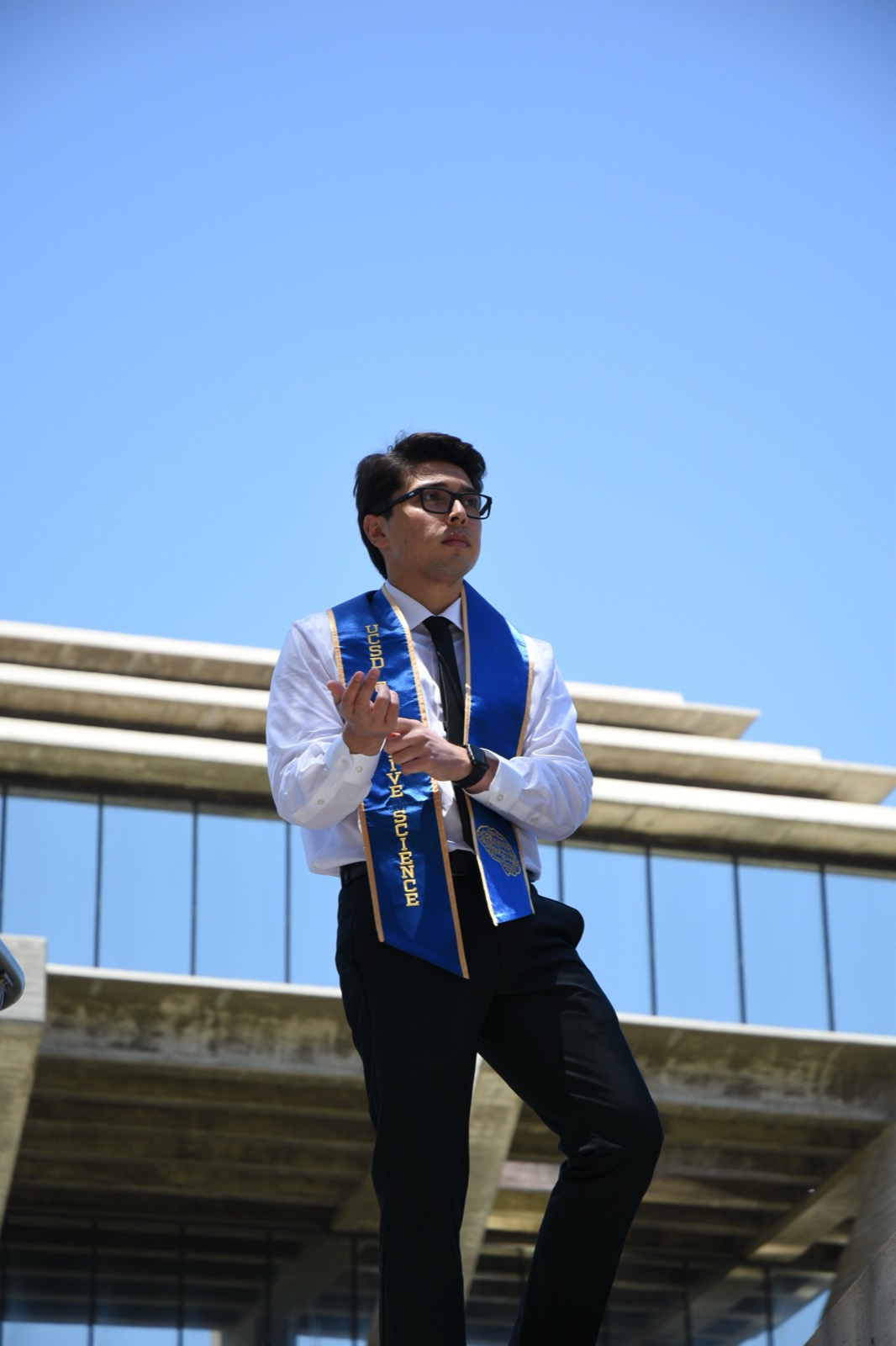 Graduation portrait in a UC San Diego stole, shot from below against the sky