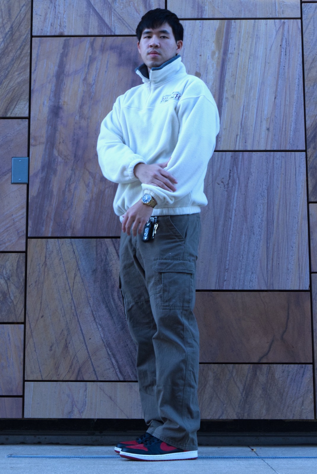 Full-length portrait against a patterned stone wall