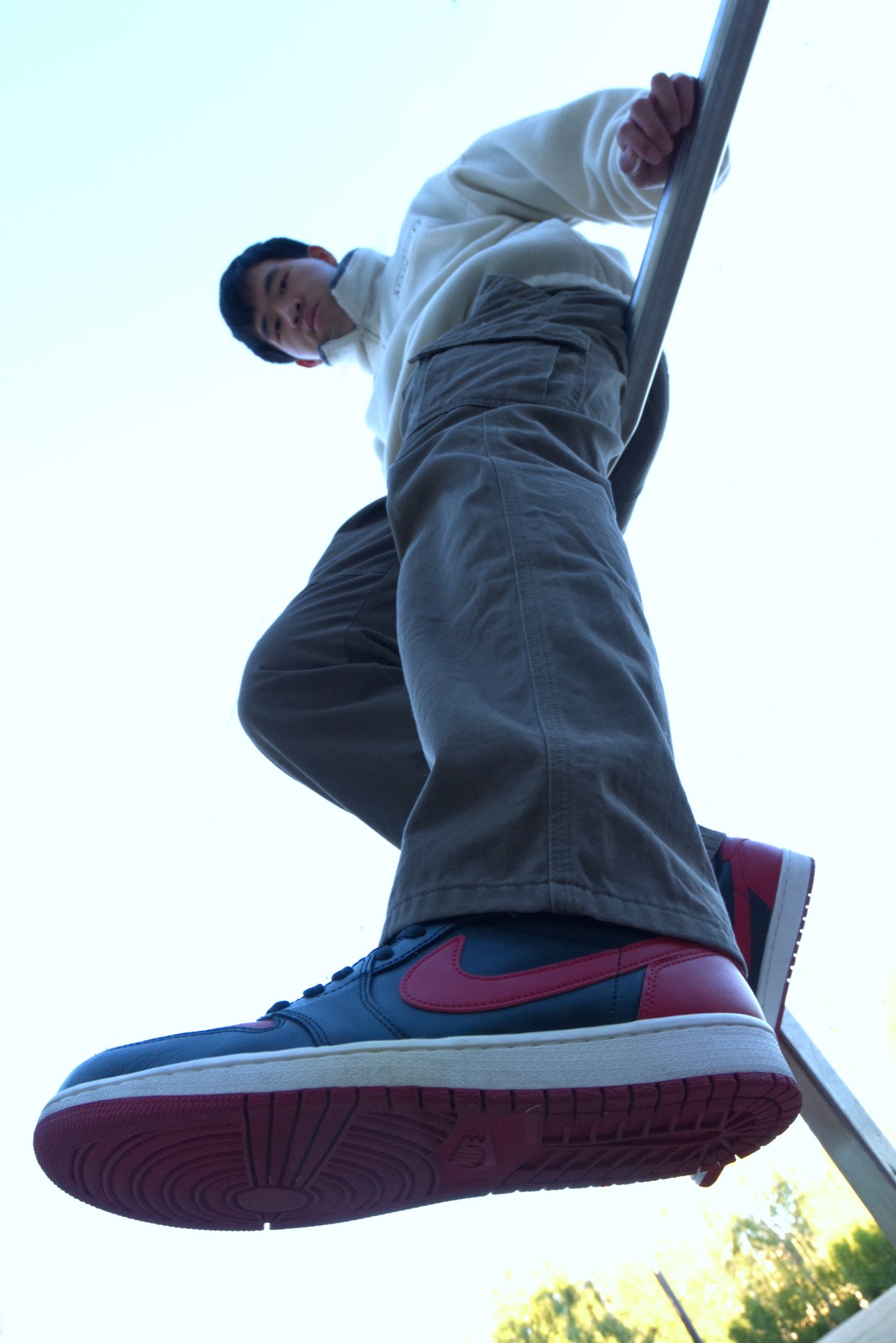 Low-angle portrait shot upward against a bright sky